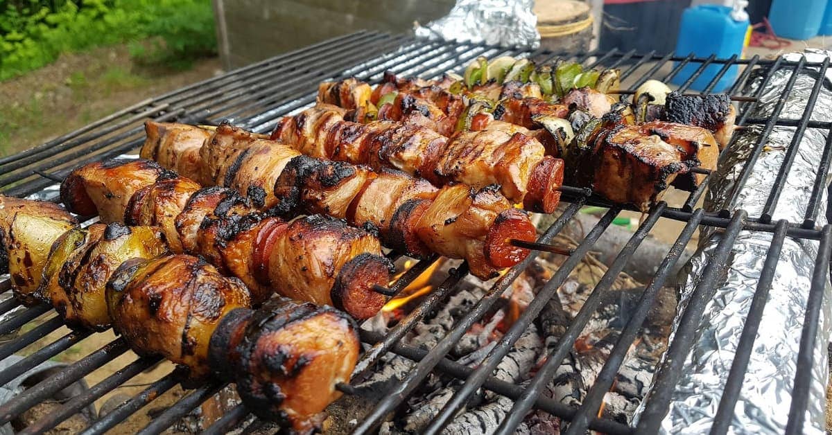 viande avec de la fumée sur la grille du barbecue. la viande de porc frite,  le boeuf, l'agneau sur les brochettes sont frits au feu, les brochettes sur  une brochette en métal